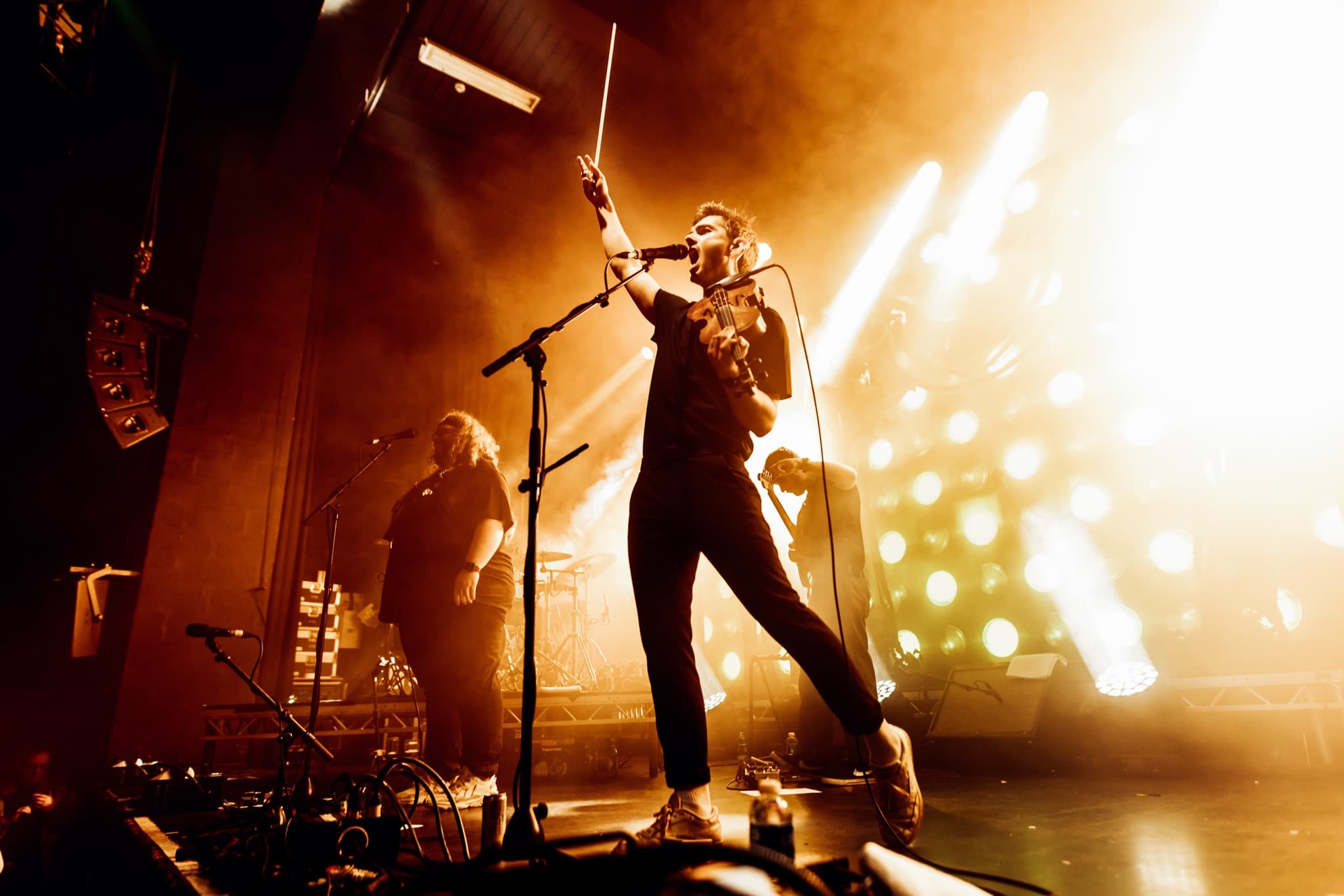 Fiddler Euan Smillie performs on stage, surrounded by his band members.