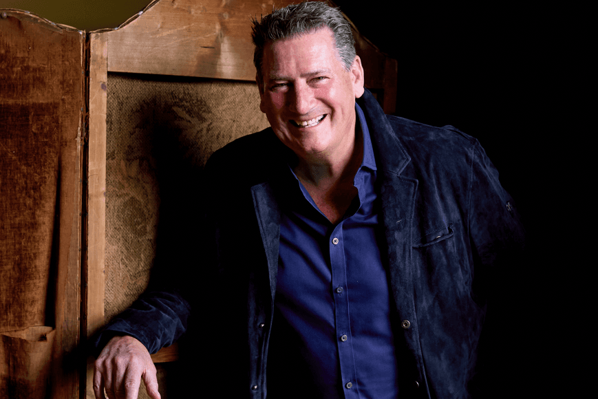 Tony Hadley smiling wearing dark blue shirt with navy jacket